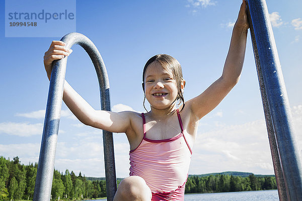 Junges Mädchen im Badeanzug steigt über eine Leiter aus einem See  Schweden