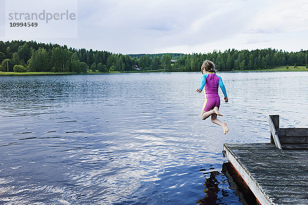 Mädchen springt vom Steg in den See  Schweden