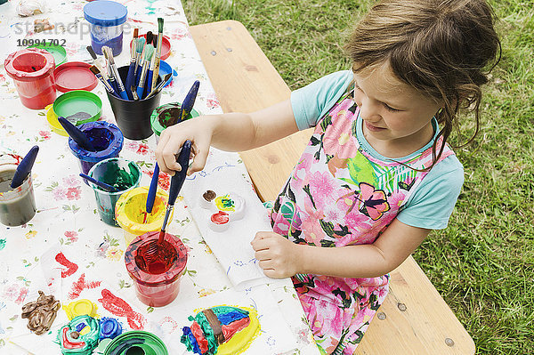 5 Jahre altes Mädchen malt an einem Tisch im Garten  Schweden