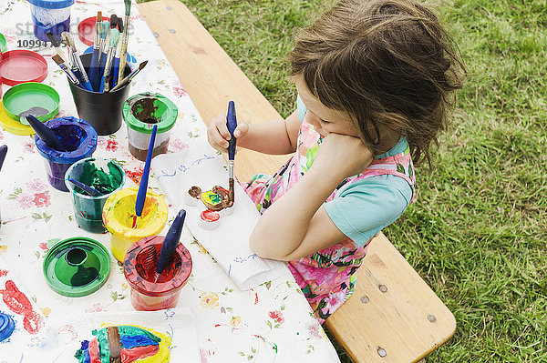 5 Jahre altes Mädchen malt an einem Tisch im Garten  Schweden