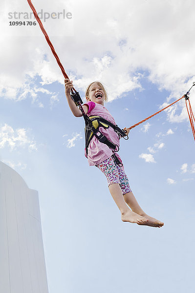 6-jähriges Mädchen springt mit einem Bungee-Trampolin an einem sonnigen Tag  Deutschland