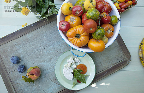 Draufsicht auf eine Schüssel mit Heirloom-Tomaten und einen Teller mit Feta-Käse und frischem Basilikum