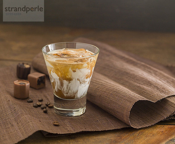 Eiskaffeegetränk im Glas mit Schokolade und Kaffeebohnen an der Seite