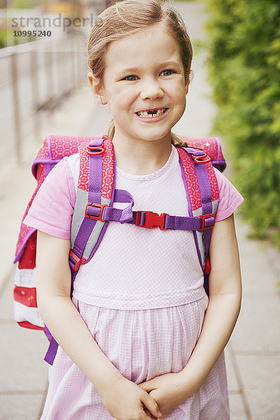 5 Jahre altes Schulmädchen mit rosa Schultasche lächelnd mit fehlenden Zähnen
