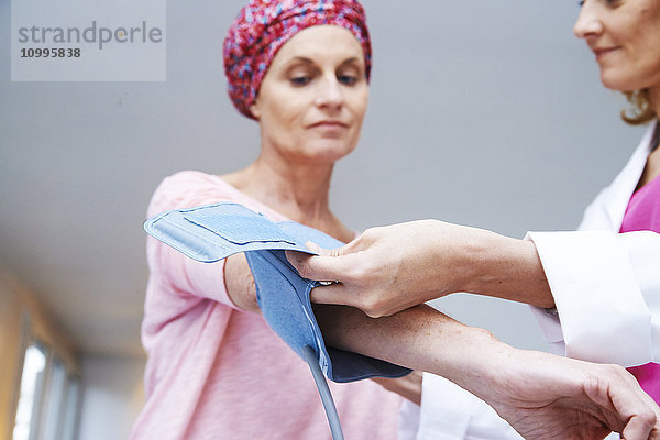 Ein Arzt misst den Blutdruck einer Frau  die an Krebs leidet.