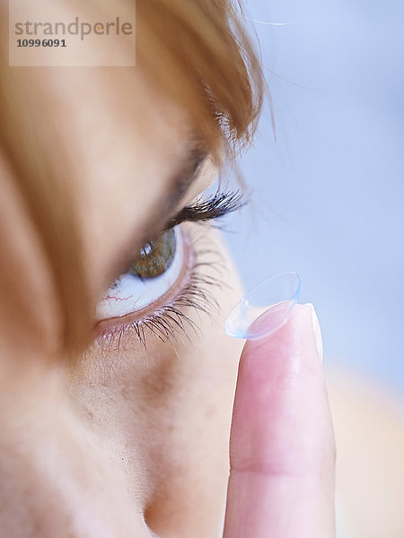 Frau beim Einsetzen einer Kontaktlinse.