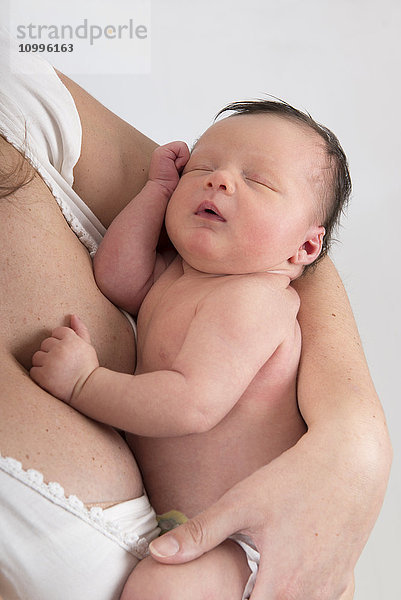 Ein schlafendes Baby in den Armen der Mutter.