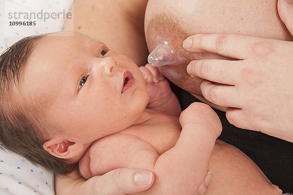 Mutter  die ihr Baby mit einem Silikon-Brustwarzenschutz stillt.