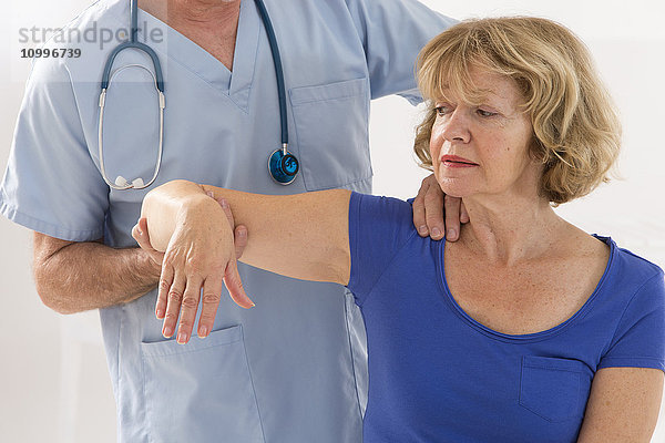 Arzt bei der Untersuchung der Schulter eines Patienten.