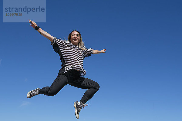 Junge Frau springt gegen den klaren Himmel