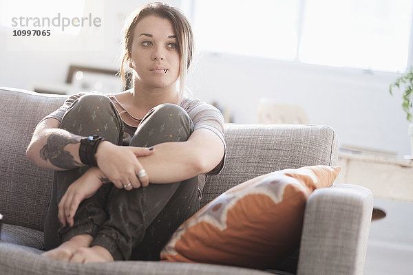 Traurige Frau sitzt auf dem Sofa im Wohnzimmer