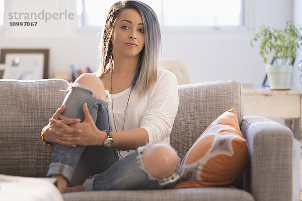 Selbstbewusste junge Frau auf dem Sofa sitzend