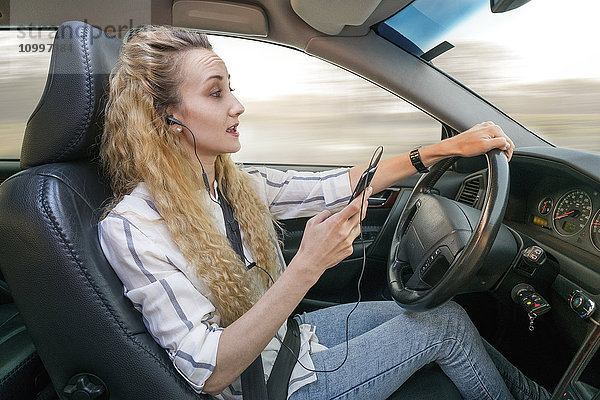 Frau benutzt Mobiltelefon beim Autofahren