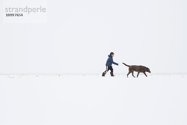 Junge (6-7) beim Spaziergang mit Hund im Winter