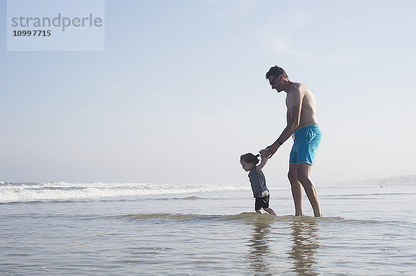 Vater mit Tochter (18-23 Monate) beim Waten im Meer