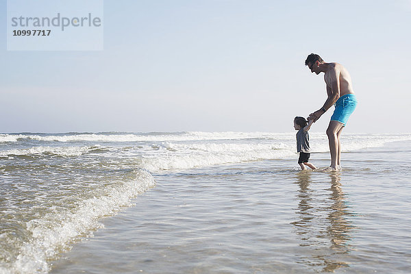 Vater mit Tochter (18-23 Monate) beim Waten im Meer