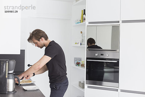 Ein Mann im mittleren Erwachsenenalter bereitet das Frühstück in einer modernen Küche vor
