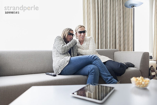 Frauen mit 3D-Brille sitzen auf dem Sofa im Wohnzimmer