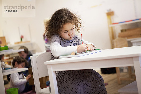 Reportage in einer zweisprachigen Montessori-Schule in Haute-Savoie  Frankreich  die Kinder im Alter von 2 bis 6 Jahren unterrichtet. Die 2- bis 6-Jährigen sind alle in einer Klasse  um die Sozialisierung zu fördern: die Älteren kümmern sich um die Jüngeren  was das Selbstvertrauen der Älteren stärkt und die Motivation der Jüngeren erhöht. Die in der Schule angewandte Montessori-Pädagogik zielt darauf ab  die Autonomie  den Wunsch und die Neugier des Kindes zu entwickeln. Jede nutzlose Hilfe  die dem Kind gegeben wird  wird zu einem Hindernis für seine Entwicklung   sagte Maria Montessori. Den Kindern stehen bestimmte Materialien zur Verfügung  und jedes Kind kann die Übung auswählen  die es durchführen möchte. Bei dieser Übung muss das Kind kleine Löcher machen  indem es den Punkten folgt  um eine Pappform abzutrennen.
