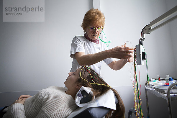 Reportage in einer funktionellen neurologischen Untersuchungseinheit. Epilepsie-Screening und Folgeberatung. Die Patienten machen ein Video-EEG (Elektroenzephalogramm)  bei dem sie verschiedenen akustischen und visuellen Reizen ausgesetzt werden. Die Muster werden anschließend vom Neurologen analysiert. Eine Krankenschwester legt die Elektroden an.