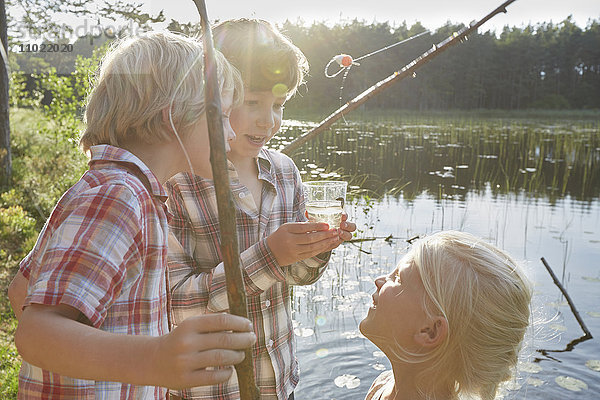 Brüder und Schwestern beim Fischen am sonnigen Teich