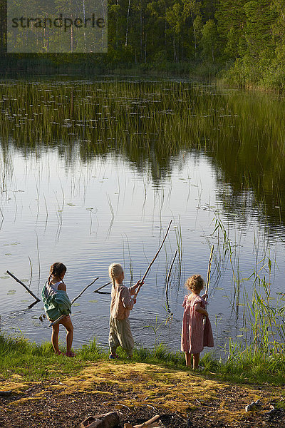 Mädchen fischen am sonnigen Seeufer