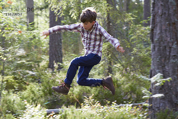 Energetischer Junge beim Springen im Wald