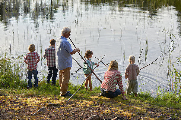 Großeltern und Enkelkinder fischen am Seeufer