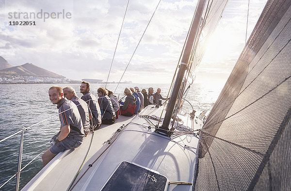 Pensionierte Freunde sitzen auf einem Segelboot auf dem sonnigen Meer.