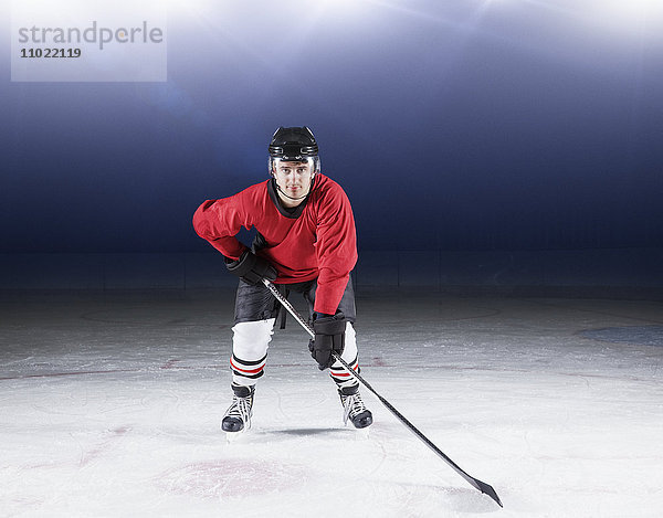 Porträtbestimmter Hockeyspieler in roter Uniform auf Eis