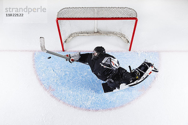 Overhead-Ansicht Hockey-Torwart erreicht Puck am Tornetz zu blockieren