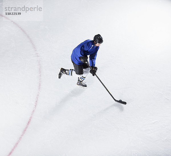 Hockeyspieler in blauer Uniform mit Puck auf Eis