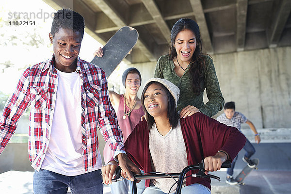 Jugendfreunde mit Skateboards und BMX-Fahrrad im Skatepark