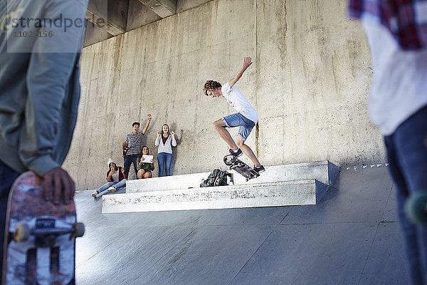 Freunde beobachten und jubeln Jugendliche beim Skateboarden im Skatepark.