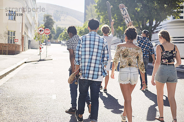 Teenager-Freunde mit Skateboards auf der sonnigen Stadtstraße