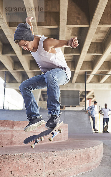 Teenager Junge springt Skateboard im Skatepark