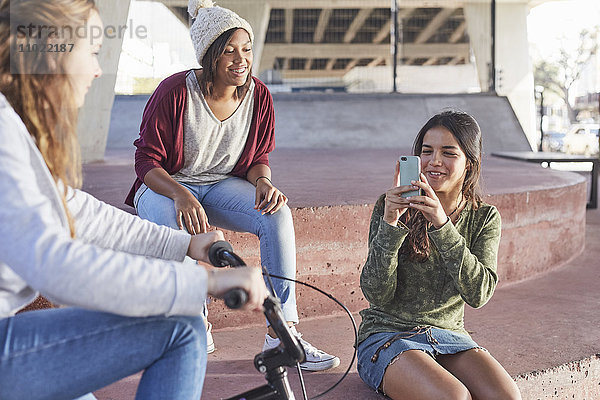 Teenager-Mädchen mit Fotohandy im Skatepark