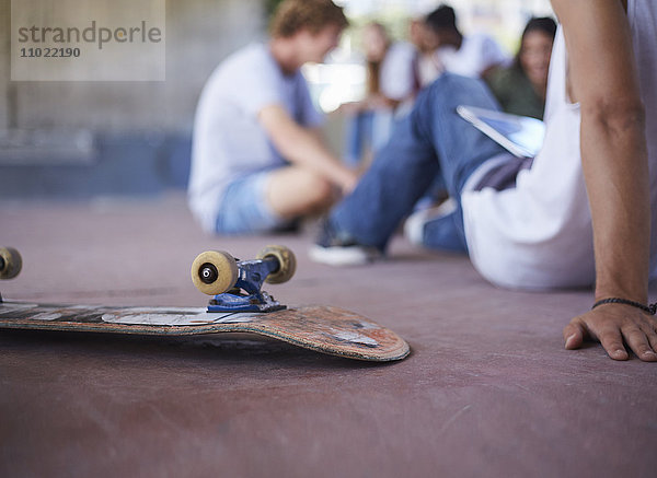 Skateboard umgedreht neben Teenager-Freunden im Skatepark