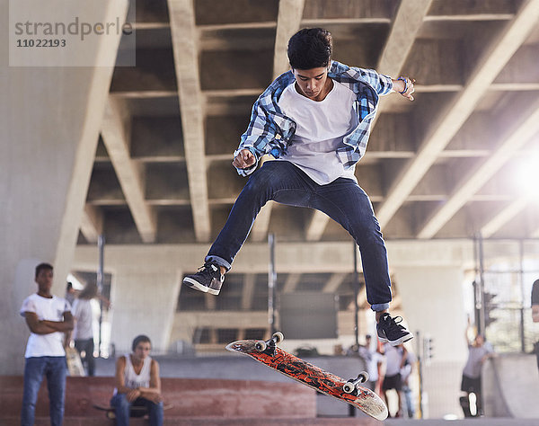 Freunde sehen dem Teenager beim Skateboardfahren im Skatepark zu.