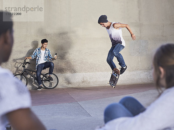 Freunde sehen dem Teenager beim Skateboardfahren im Skatepark zu.