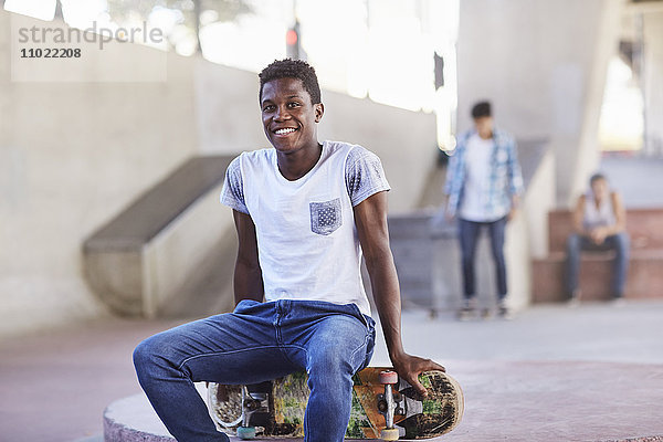 Porträt lächelnder Teenager auf dem Skateboard im Skatepark