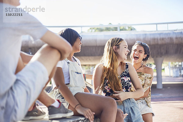Teenagermädchen lachen im sonnigen Skatepark