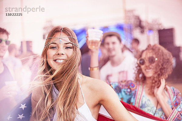 Portrait lächelnde junge Frau mit amerikanischer Flagge beim Musikfestival