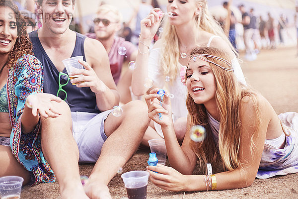 Junge Freunde hängen auf dem Musikfestival herum und blasen Blasen.