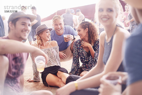 Junge Freunde beim Bier trinken und beim Musikfestival plaudern