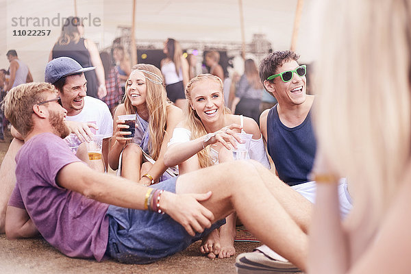 Junge Freunde beim Trinken und Reden auf dem Musikfestival