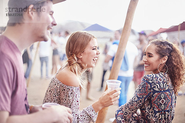 Junge Freunde lachen und trinken beim Musikfestival