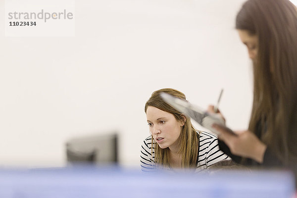 Geschäftsfrauen mit Klemmbrett am Computer