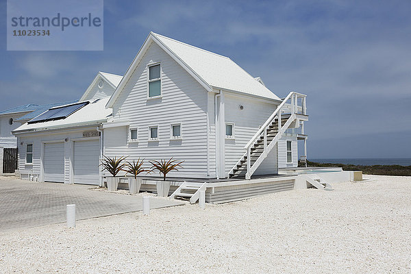 Weißes Strandhaus unter sonnigem blauem Himmel