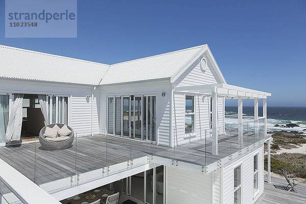 Weißes Strandhaus mit Balkon mit Meerblick unter sonnigem blauem Himmel